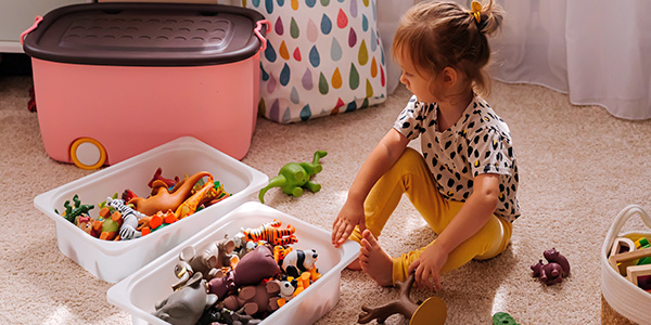 criança sentada no chão organizando brinquedos