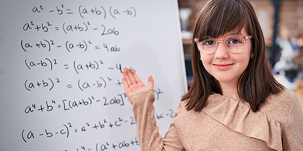 Menina de frente ao quadro com contas matemáticas