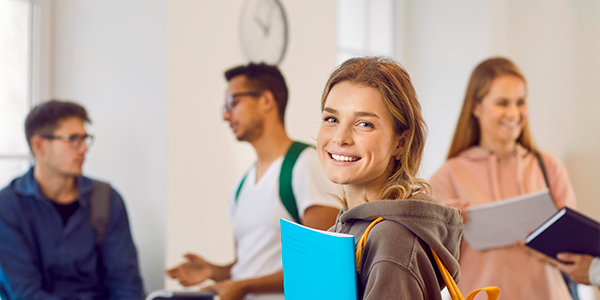 Moça com caderno no braço e sorriso no rosto estudando para o Enem 