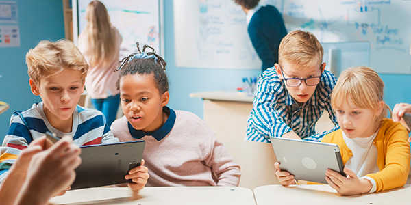 Meninos vendo o tablet durante a aula é a gamificação inovando a educação. 