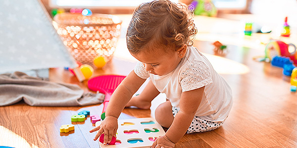 Menina com 1 ou 2 anos, sentada em seu quarto brincando